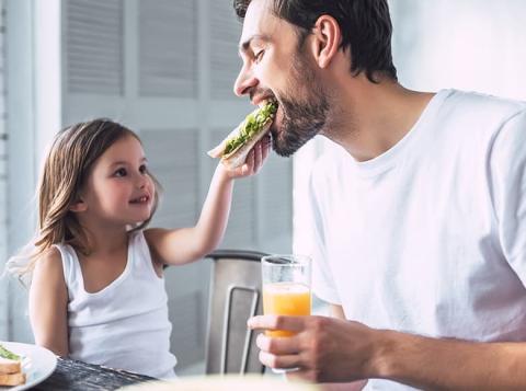 Daughter feeding father a sandwich